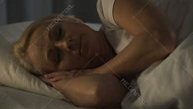 Middle-aged woman smiling sleeping with sound sleep, feeling calm and bliss