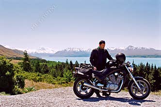 Motorcycle rider near mountain and lake