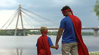 Father and son wearing funny superhero costumes looking afar, supportive parent