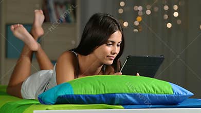 Teen using a tablet on a bed at home