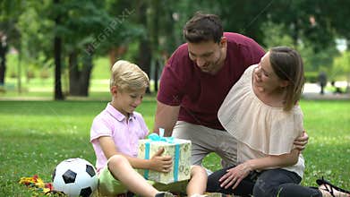 Sad boy sitting lonely in park, parents give him gift to support and cheer up