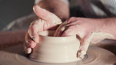Creating earthenware and traditional pottery concept. Experienced male potter`s hands creating beautiful clay product -