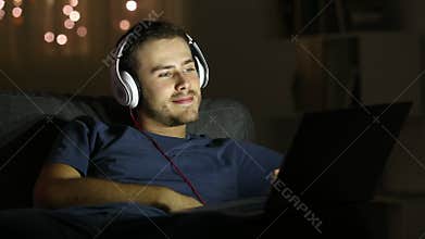 Happy man watching videos in a laptop in the night