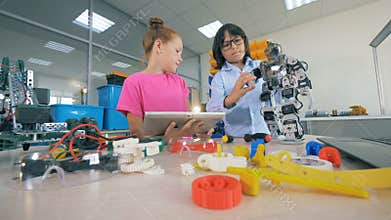 Children try to make a robot on a table, using tools. 4K.