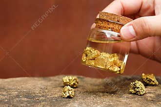 Human hands are holding bottles that contain pure gold
