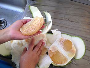 Peel grapefruit using a kitchen knife on a sink.