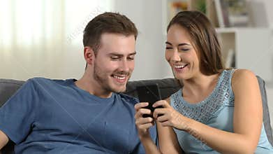 Happy couple talking about phone content at home