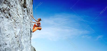Young slim woman rock climber climbing on the cliff