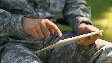 Soldier using tablet outdoors, online psychological support service for veterans