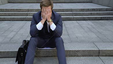 Upset man sitting on stairs, lost money on stock market, bankruptcy, dismissal