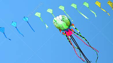 Colorful kite flying against a blue sky and sun