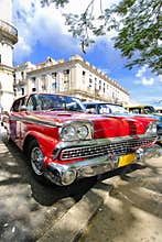 Red car under tree branches in havana, cuba