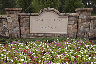 Blank Sign in Rock Wall Surrounded by Flowers and Trees