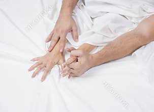 Close up of passionate couple hold hands during making intense love in bedroom, lovers enjoy hot sex on white sheet