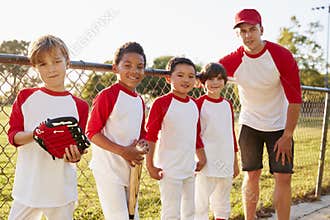 Coach and young boys in a baseball team looking to camera