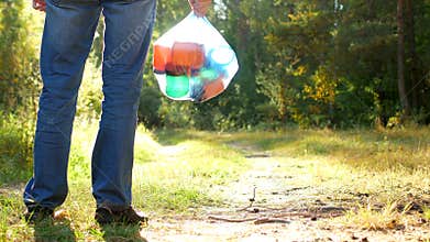 A man in a forest clearing stands with a package of garbage in his hands, a garbage collector, garbage and nature, close