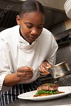 Chef Adding Sauce To Dish In Restaurant Kitchen