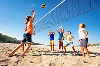 Boys and girls playing volleyball on the beach