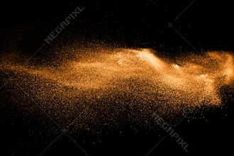 Orange dust particles explosion on black background.