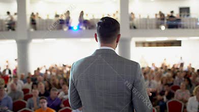 Speaker giving a talk on corporate Business Conference. Audience at the conference hall. Business event. A young man in