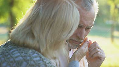 Retired woman embracing ill husband, support and care, family togetherness
