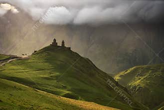 Sunrise at the Gergeti Trinity Church with sunrays of Kazbegi mountain in Georgia