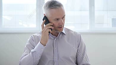 Upset middle aged man listening on phone