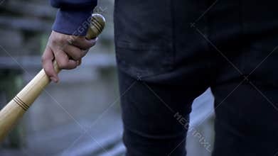 Vandalism, young man walking on stadium tribune with baseball bat, youth gang