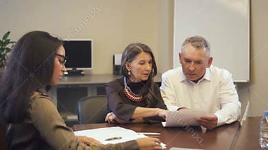 Mature family couple buying property and discussing mortgage contract with african-american saleswoman.