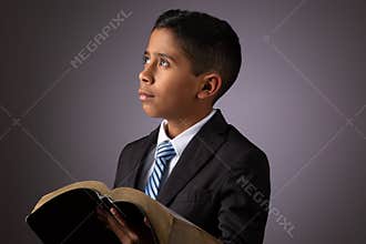 Little Hispanic Boy Looking Away while Holding the Holy Scriptures, The Word of God, The Bible