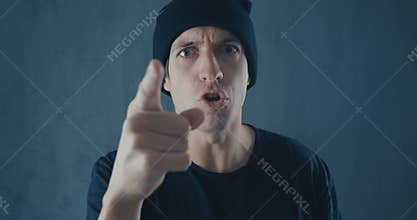Portrait of angry man in black cap screaming with agression. Threat of violence.