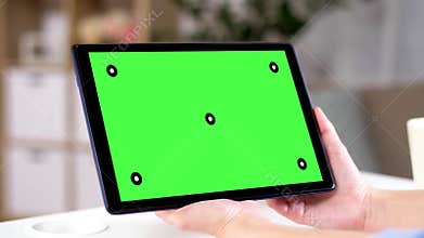 Hands holding tablet pc with green screen at home