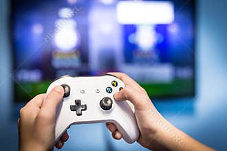 Video gaming and game play on tv fun gamer holding game-pad and controller video console playing and enjoying with blurred screen