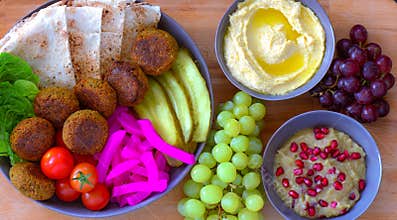 Falafel platter in blue bowl served with grapes, hummus and baba ganoush