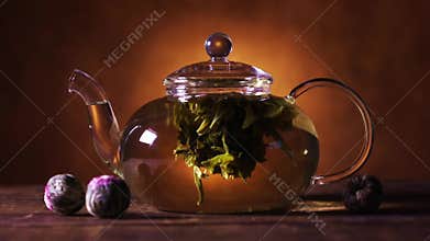 Green Chinese tea flower bud blooming in glass teapot