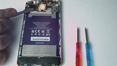 Close up view of male hand holding used Phone battery to repair and replace battery Phone.