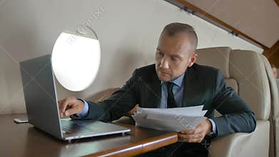 Handsome male with macbook surfing in Internet inside of luxury interior of private jet