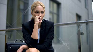 Anxious woman sitting on bench, worried about dismissal from work, depression