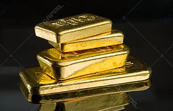 Several gold bars of different weight on a dark mirror surface
