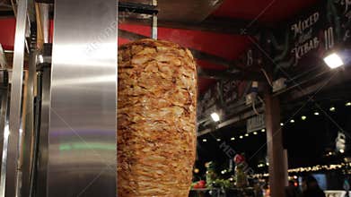 Shish kebab on skewer turning on spit while cooking Turkish traditional food