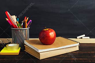 Teacher`s desk with writing materials, a book and an apple, a blank for text or a background for a school theme. Copy space