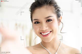 Closeup portrait of beautiful Asian woman in elegant white wedding dress make selfie recording video vlog from hands with
