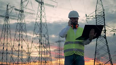 Electrical transmission line and a male worker speaking on a phone