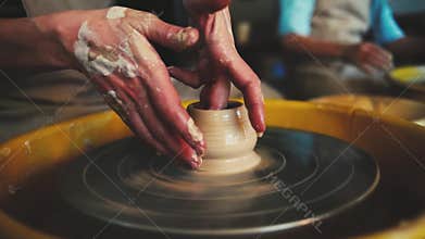 Potter`s wheel in the pottery workshop. Handcraft Pottery inside. womans Hands working on pottery wheel, shaping a clay