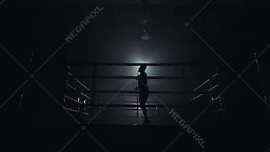 Male boxer wrapped in bandage jumping on the skipping rope in the dark ring. Slow motion. Silhouette. Boxing concept.