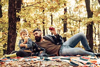Healthy snack. Bite juicy apple. Family picnic. Hipster bearded dad with son spend time in forest. Brutal bearded man