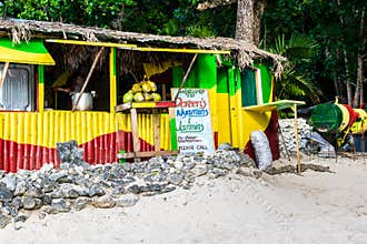 Jamaican man serving soup cooking on open fire pot in traditional outdoor beach vendor cook shop