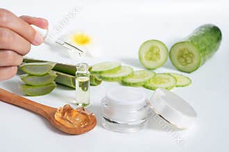 Organic natural skincare concept. open blank cosmetic cream jar with white cream texture inside and hand holding glass dropper