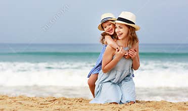 Happy family at beach. mother and child daughter hug at sea