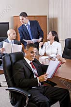 Hispanic man with report, colleagues conversing
